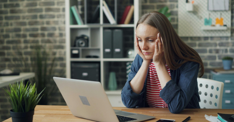 The woman looks thoughtfully and anxiously at her laptop and wonders whether she will be able to finish the presentation in time.