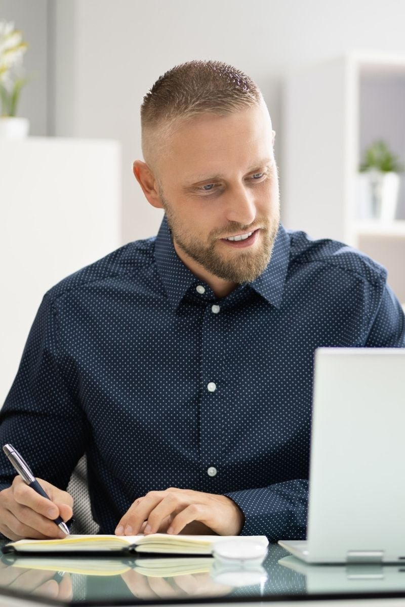 Mann sitzt am Rechner und schaut ein Webinar