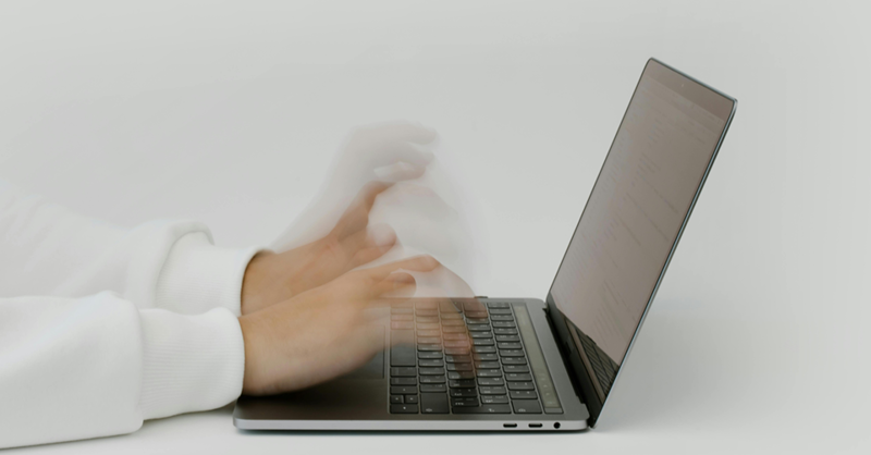 A man types a text on his laptop in a relaxed office atmosphere.